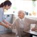 Pleasant caregiver helping aged woman to stand up