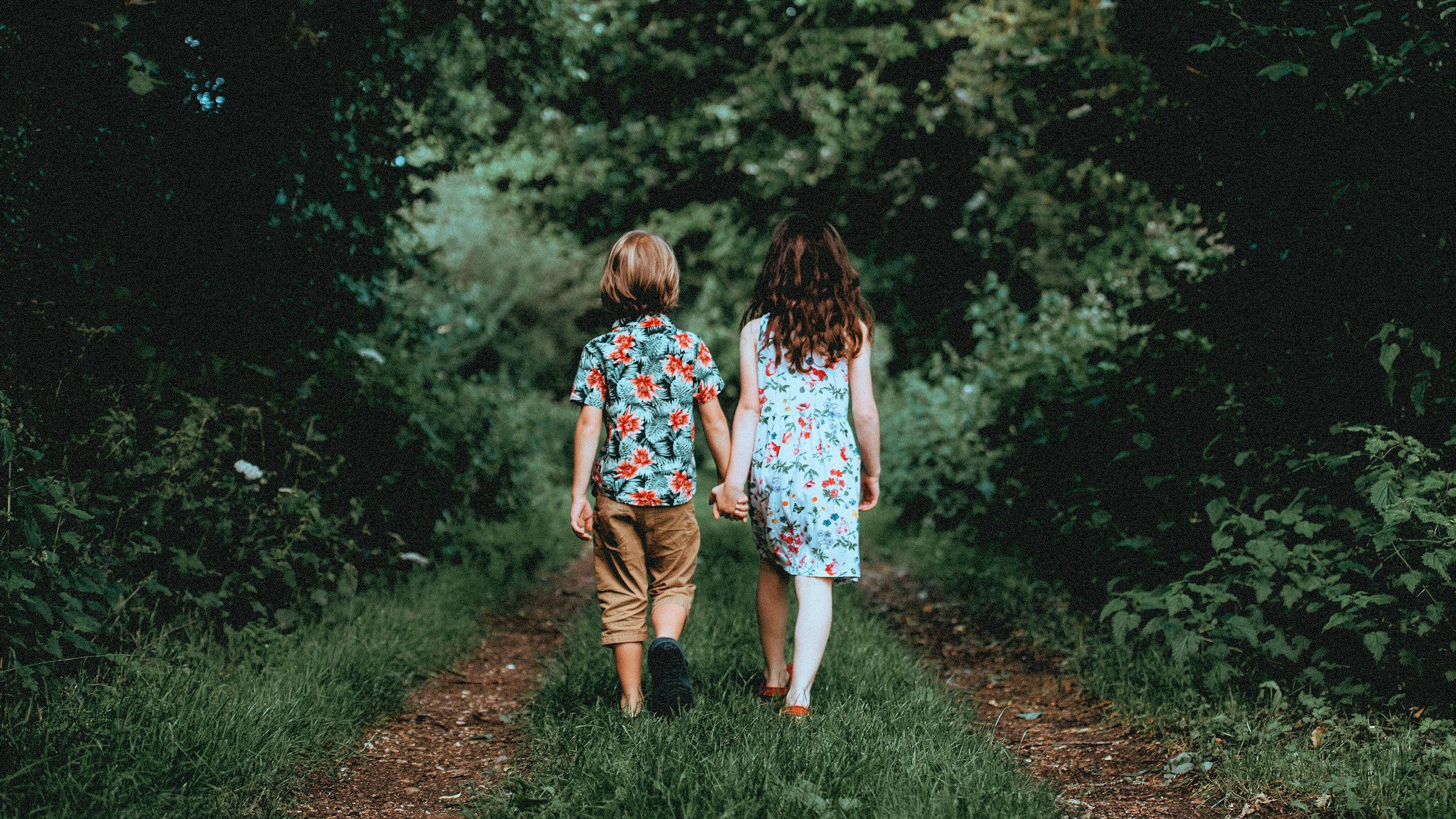 Boy girl children walking in woods