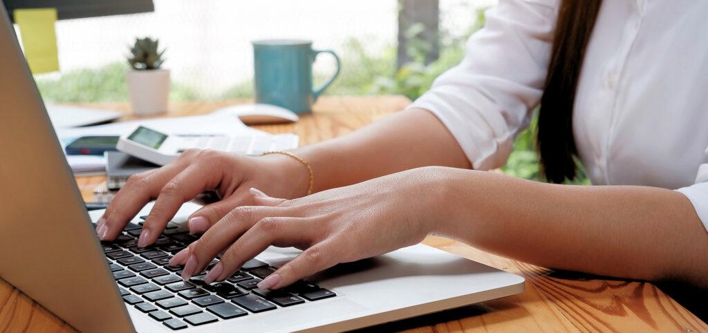 Woman typing sunlight desk laptop